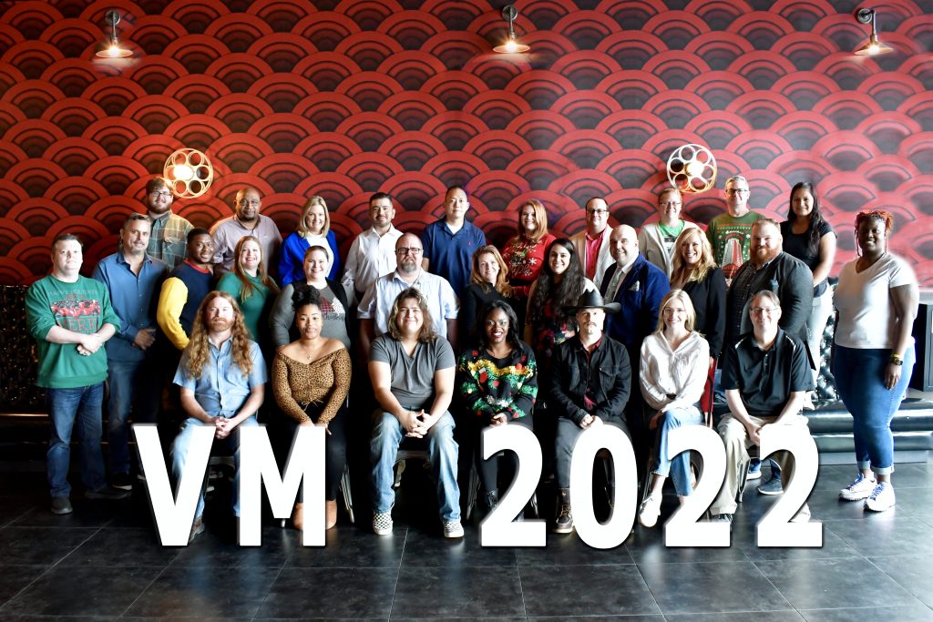 A photo of a group of Visual Matrix employees in front of a sign saying VM 2022